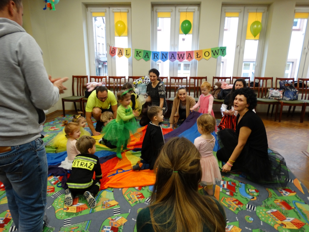Grupa dzieci siedząca na kolorowej chuście animacyjnej.