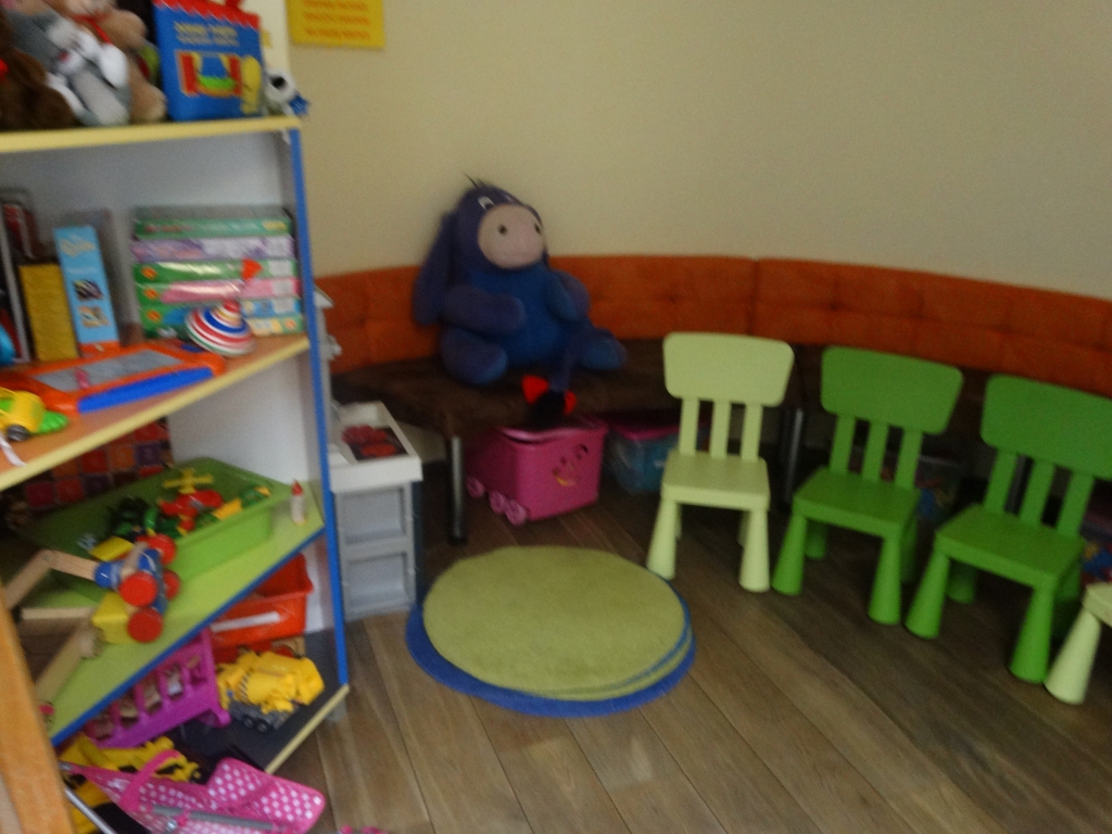 Regalik z zabawkami, duży pluszowy osiołek siedzący na ławce w kąciku dla dzieci
