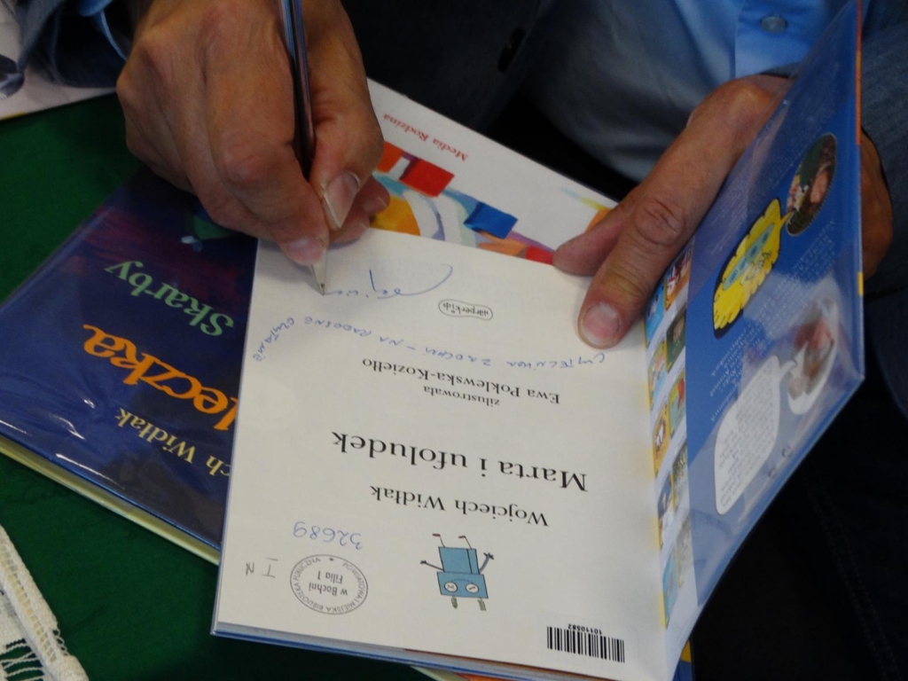 Zbliżenie na dłonie pisarza składającego autograf w książce