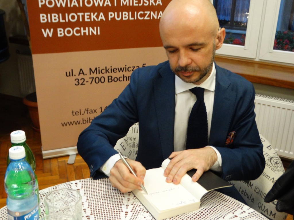Michał Majchrzak wpisuje dedykację do książki