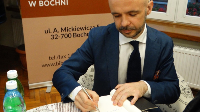 Michał Majchrzak wpisuje dedykację do książki