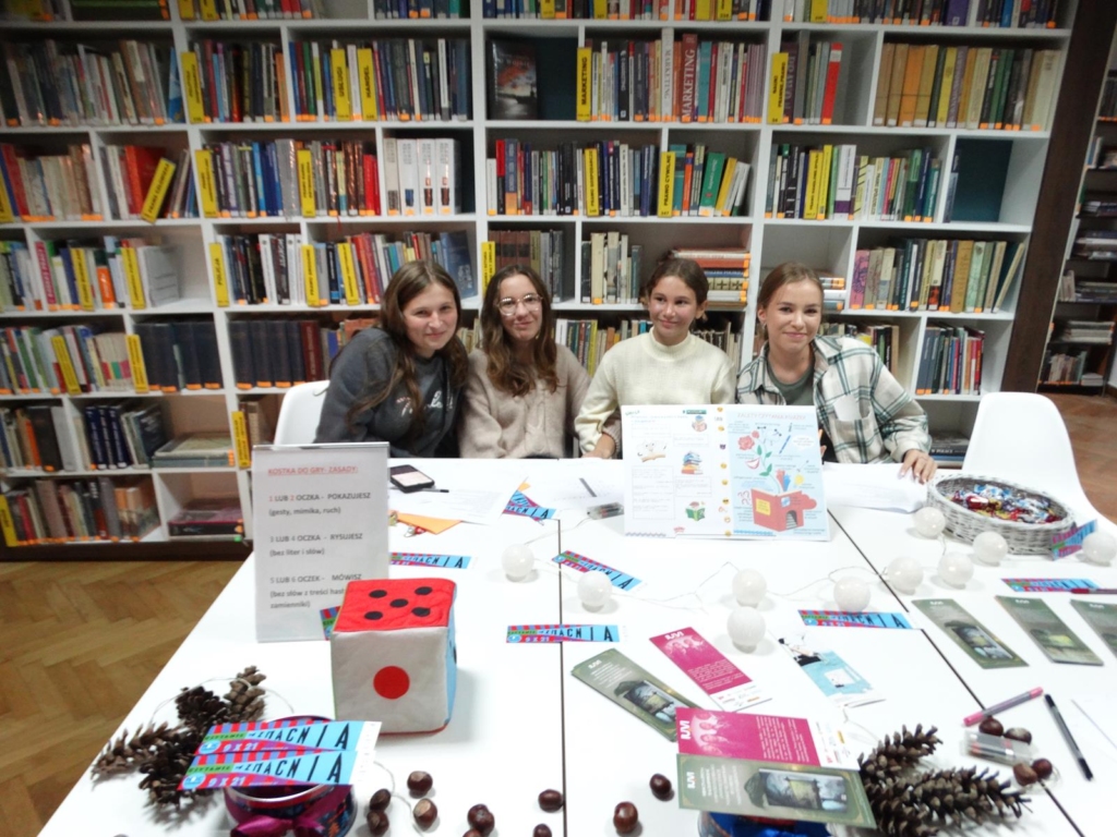 Cztery dziewczyny przy stole z zadaniami przygotowanymi na Nc Bibliotek