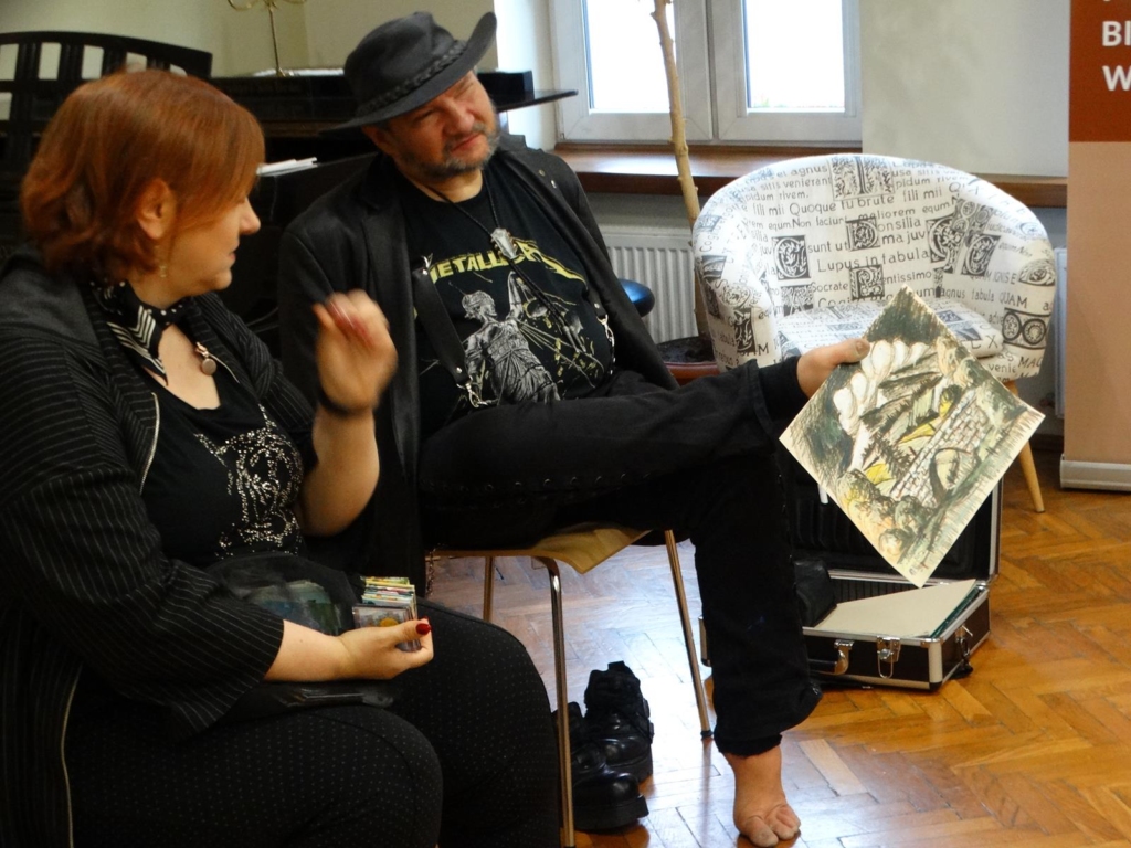 Stanisław Kmiecik prezentuje rysunek wykonany nogą w trakcie wernisażu