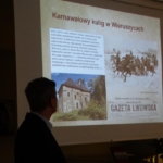 Janusz Paprota na tle ekranu z prezentacją multimedialną
